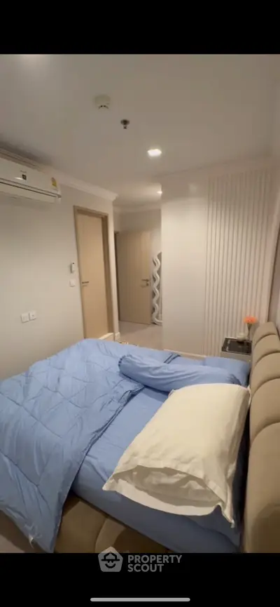 Cozy bedroom with modern decor and air conditioning, featuring a comfortable bed and stylish lighting.