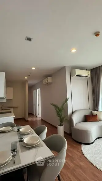 Modern living room with elegant dining area and cozy seating, featuring air conditioning and stylish decor.