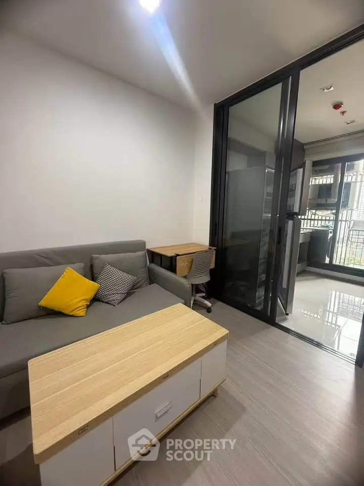 Modern living room with cozy sofa and sliding glass doors leading to balcony.