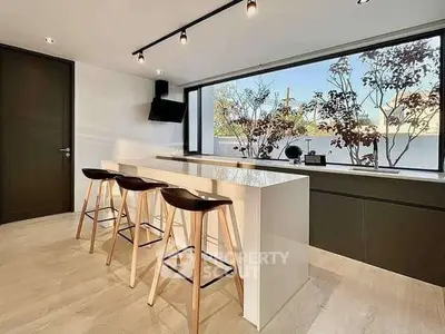 Modern kitchen with sleek island and bar stools, large window view.