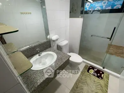 Modern bathroom with glass shower and granite countertop in stylish home.