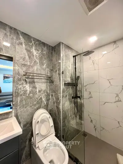 Luxurious modern bathroom with marble walls and glass shower enclosure