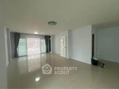 Spacious unfurnished living room with large windows and tiled flooring in modern apartment.