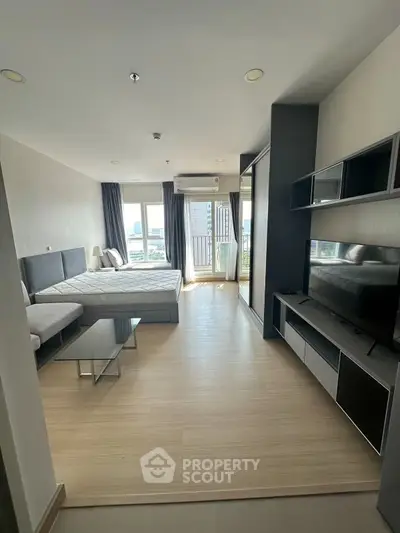 Modern bedroom with balcony view in a stylish apartment, featuring sleek furniture and ample natural light.