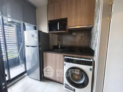 Modern kitchen with sleek appliances and balcony view, featuring a washing machine and refrigerator.