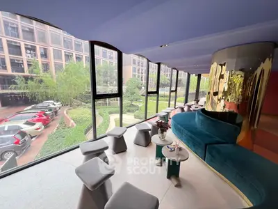 Modern lounge area with panoramic windows and stylish seating overlooking garden and parking.