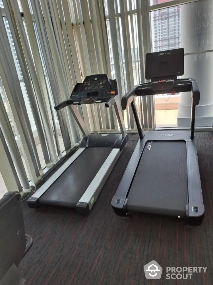 Modern gym with state-of-the-art treadmills and city view, perfect for fitness enthusiasts.