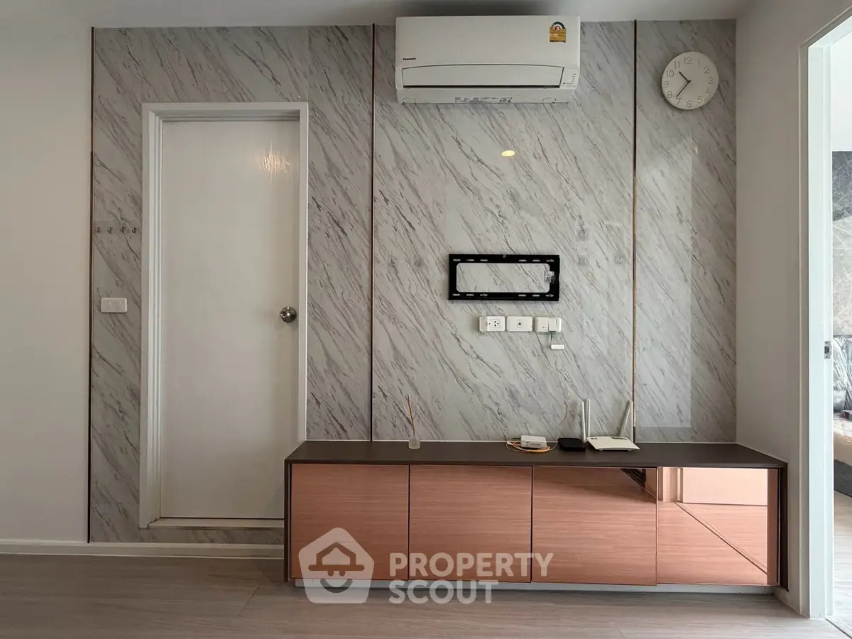 Modern living room with sleek marble wall and air conditioning unit, featuring stylish storage cabinet.
