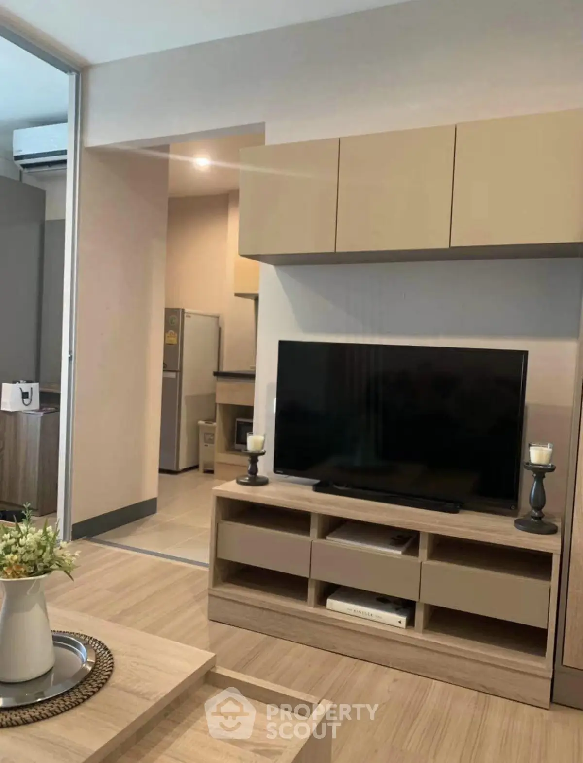 Modern living room with sleek TV unit and open kitchen layout, perfect for contemporary living.