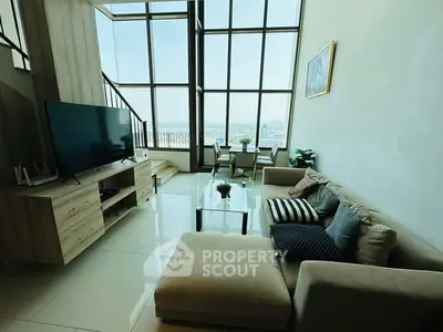 Spacious living room with high ceilings and large windows offering stunning city views.