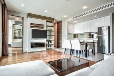 Modern open-plan living room with sleek kitchen and dining area, featuring stylish decor and ample natural light.