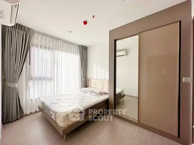 Spacious bedroom with large window and modern furnishings in a bright apartment.