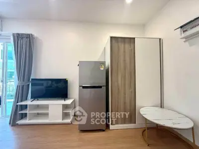 Modern living room with sleek furniture and appliances, featuring a fridge and TV stand.