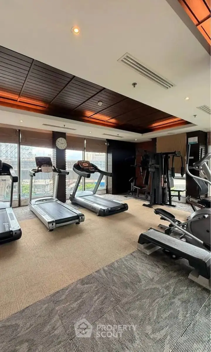 Luxurious gym with modern equipment and city view in high-end residential building.
