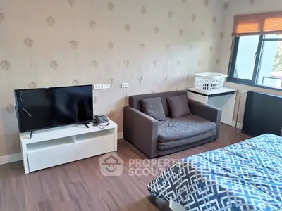 Cozy bedroom with TV and sofa, featuring modern decor and ample natural light.