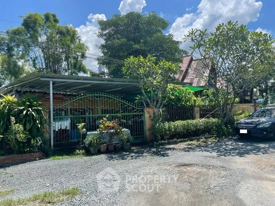 Charming suburban house with lush garden and carport under clear blue sky.