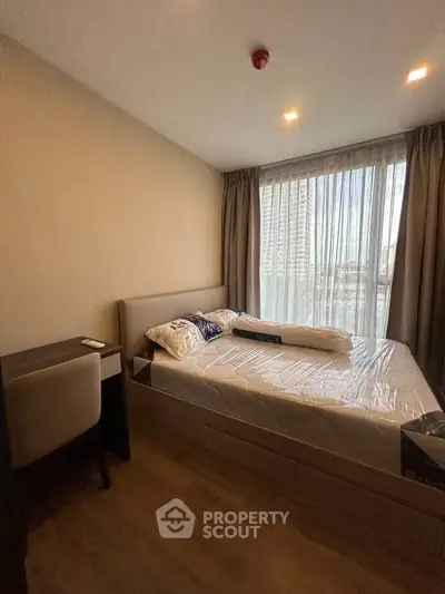 Cozy bedroom with large window and modern furnishings in a stylish apartment.