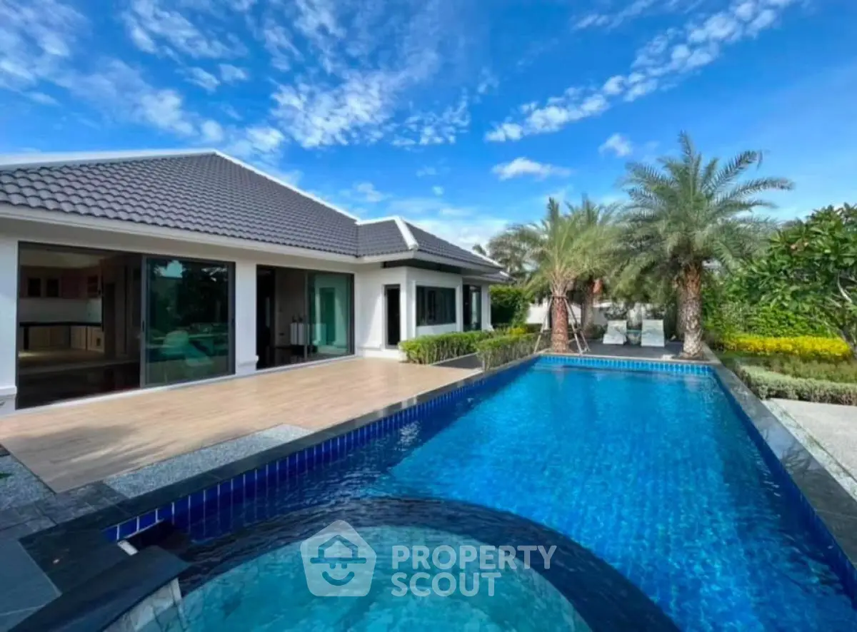 Luxurious villa with stunning pool and lush garden under clear blue sky