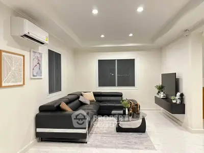 Modern living room with sleek black leather sectional sofa and wall-mounted TV, perfect for relaxation.