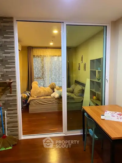 Cozy bedroom with sliding glass doors and wooden flooring, featuring a plush teddy bear and modern decor.