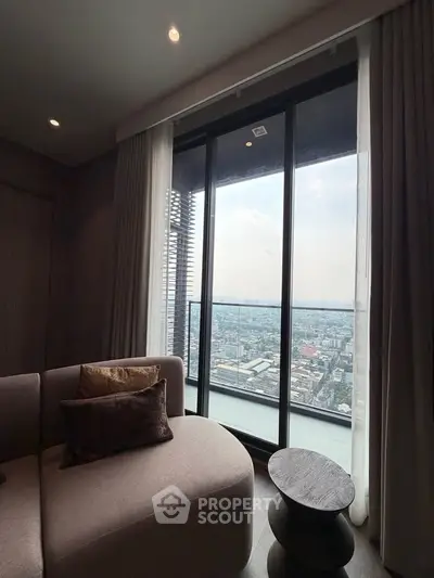 Luxurious living room with stunning city view from high-rise balcony, featuring elegant sofa and modern decor.