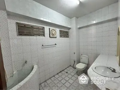 Spacious tiled bathroom with modern fixtures and ample natural light