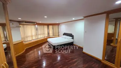 Spacious bedroom with wooden flooring and large windows in modern apartment