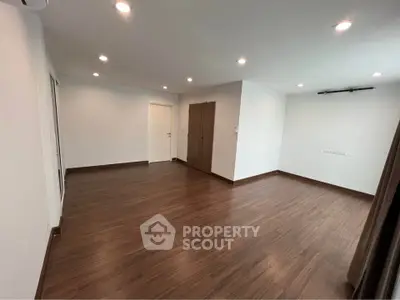 Spacious empty room with wooden flooring and recessed lighting