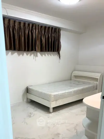 Cozy bedroom with minimalist design and natural light, featuring a single bed and elegant curtains.
