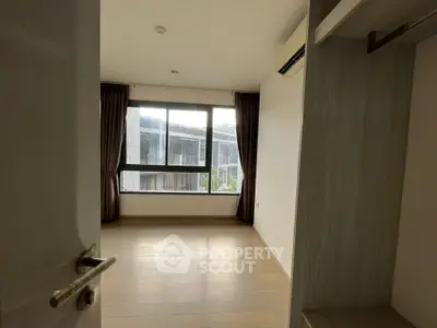 Spacious and well-lit bedroom with large windows offering ample natural light, complemented by elegant drapery and a built-in wardrobe.