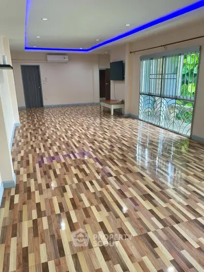 Spacious living room with modern flooring and ambient lighting, perfect for family gatherings.