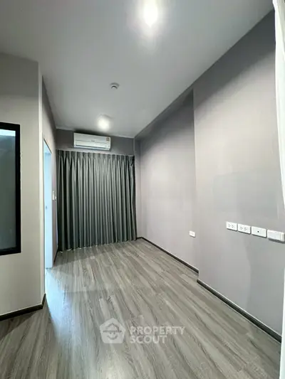 Modern empty room with sleek flooring and air conditioning, ready for customization.