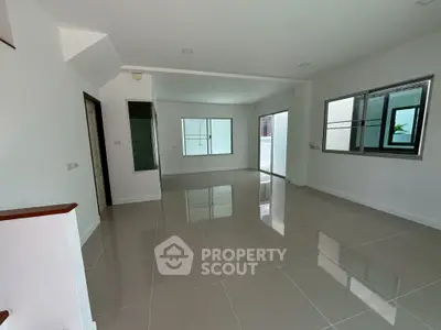 Spacious empty living room with glossy tiled floors and large windows