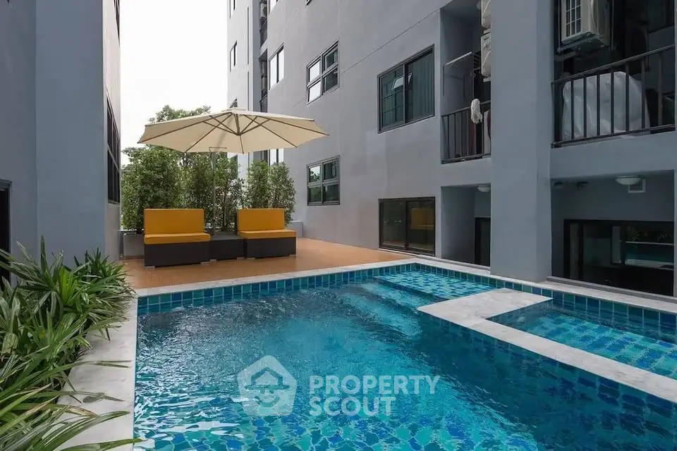 Modern apartment building with a stylish pool and cozy seating area, perfect for relaxation.
