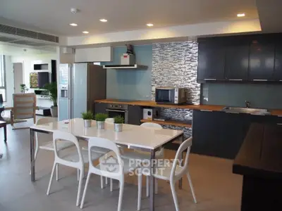 Modern kitchen with sleek cabinetry and dining area in open layout apartment