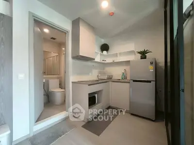 Modern compact kitchen with sleek appliances and adjacent bathroom in a stylish apartment.