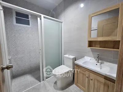 Modern bathroom with sleek design, featuring a glass shower door and stylish wooden cabinetry.