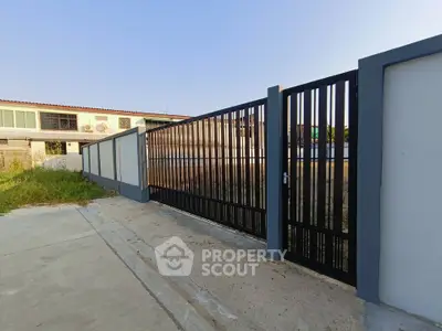 Modern gated entrance with sleek metal design and concrete driveway