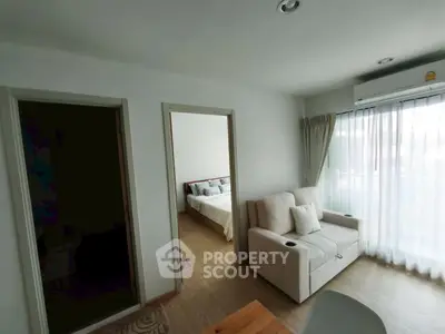 Cozy living room with natural light and adjacent bedroom in modern apartment.