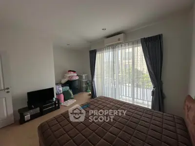 Spacious bedroom with large window and modern decor in a stylish apartment.