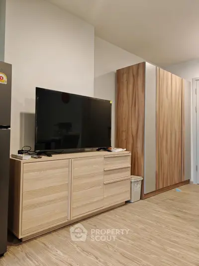 Modern living room with sleek wooden furniture and large flat-screen TV, perfect for cozy entertainment.