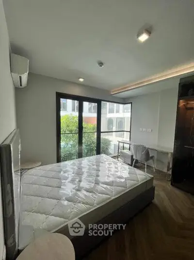 Modern bedroom with large window and natural light, featuring a comfortable bed and stylish decor.