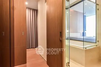 Modern bathroom with glass shower and wooden accents in luxury apartment.