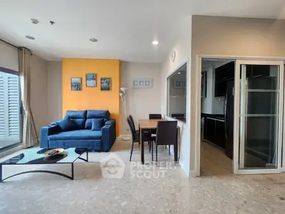 Modern living room with vibrant accent wall and sleek kitchen in open layout apartment.