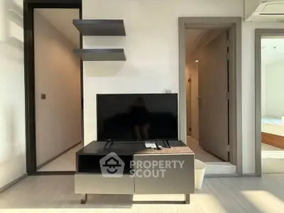 Modern living room with sleek TV stand and wall shelves, showcasing minimalist design and natural lighting.