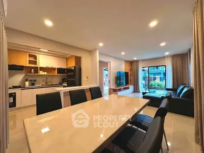 Spacious open-plan living room and kitchen with modern furnishings and large windows.