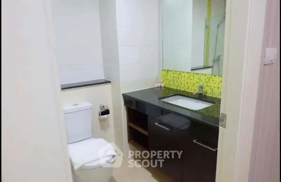 Modern bathroom with sleek black vanity and vibrant green mosaic backsplash.