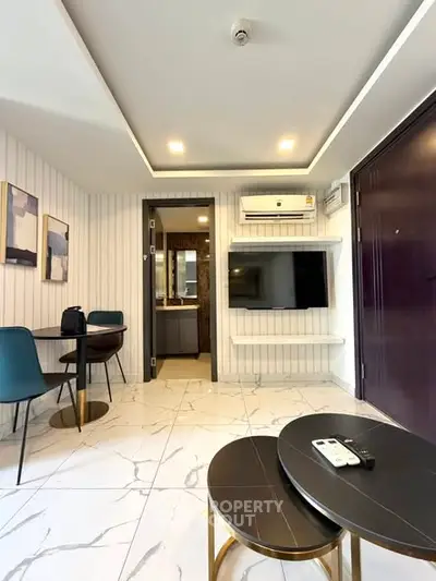 Modern living room with stylish decor and wall-mounted TV, featuring elegant furniture and marble flooring.