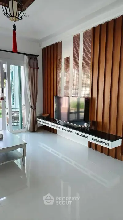 Modern living room with stylish wood paneling and large TV, featuring elegant decor and natural light.