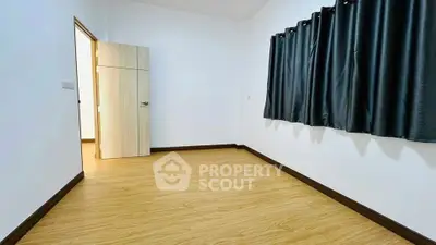 Spacious empty room with wooden flooring and dark curtains, perfect for customization.